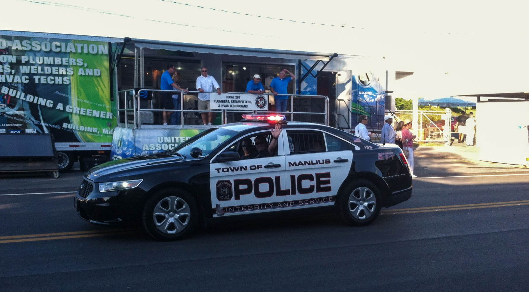 An officer waves from inside his car